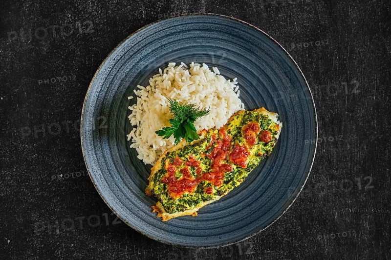 Top view of fried fillet of white fish with spinach and cheese topping and served with rice