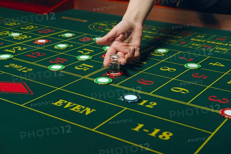 Casino roulette table with chips and cards. Winning combination. Hand of Croupier behind gambling table