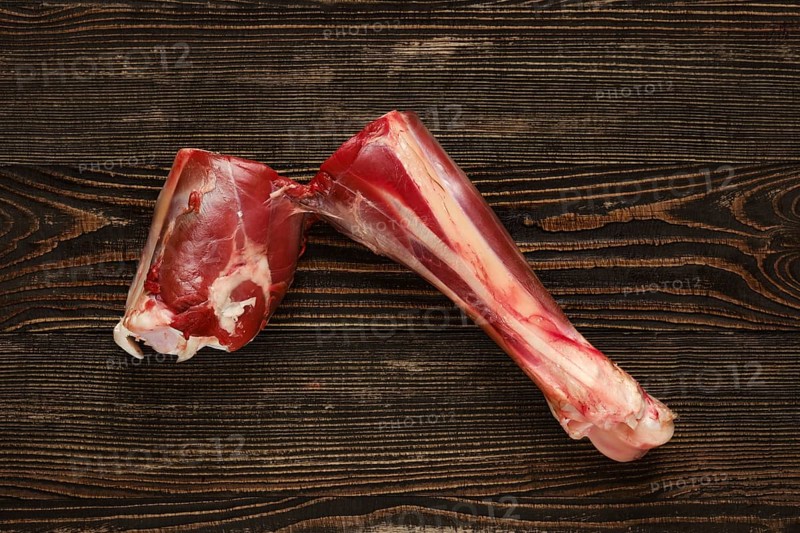 Overhead view of raw deer shank over dark wooden background