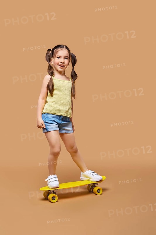 Young happy girl learning to ride on skateboard