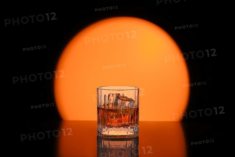 Low key photo of whiskey with ice in facetted rocks glass