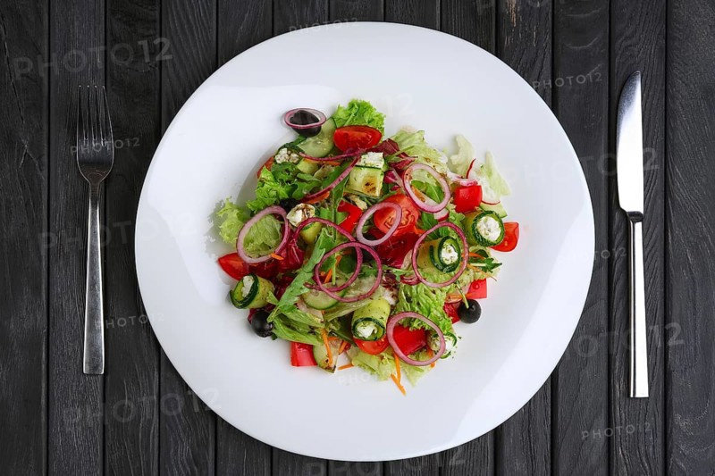 Salad with feta cheese rolled in cucumber slices with tomato and red onion