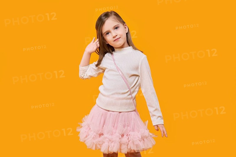 Cute little child posing on bright yellow background