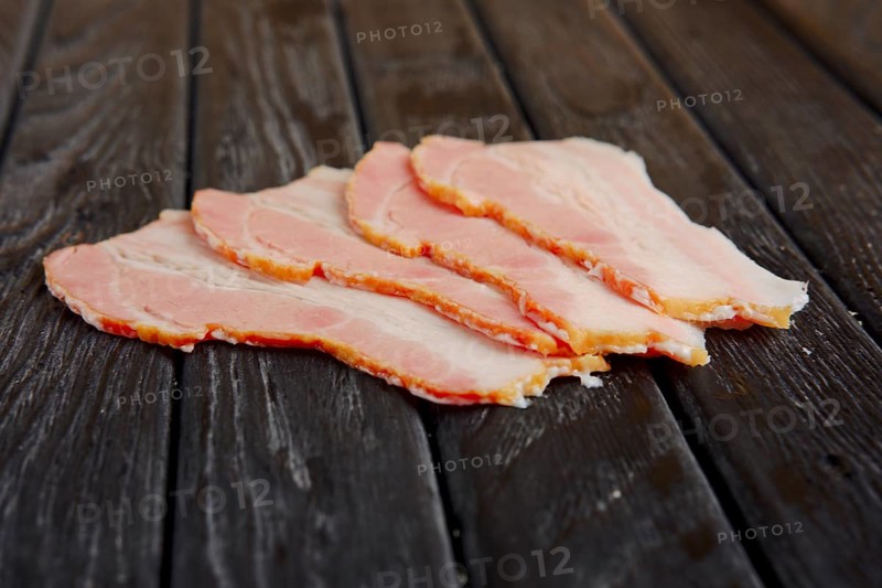 Selective focus photo of slices of fresh bacon on wooden table