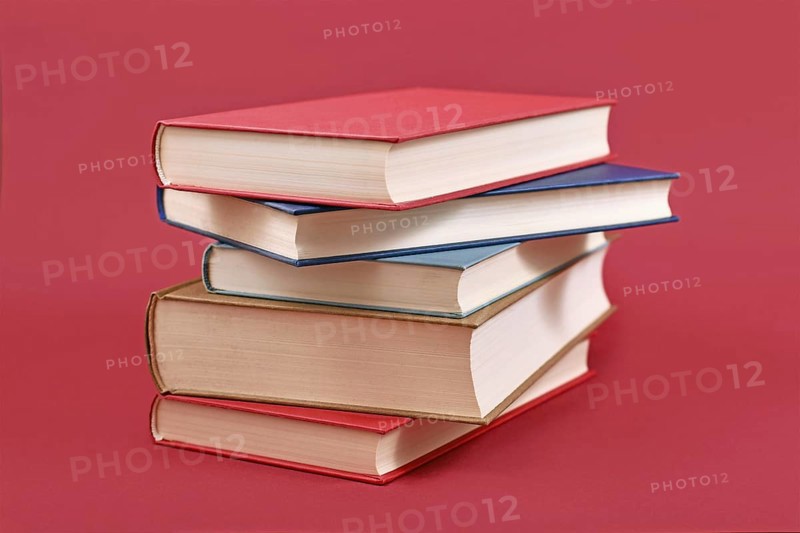 Stack of old hardcover books on dark red background