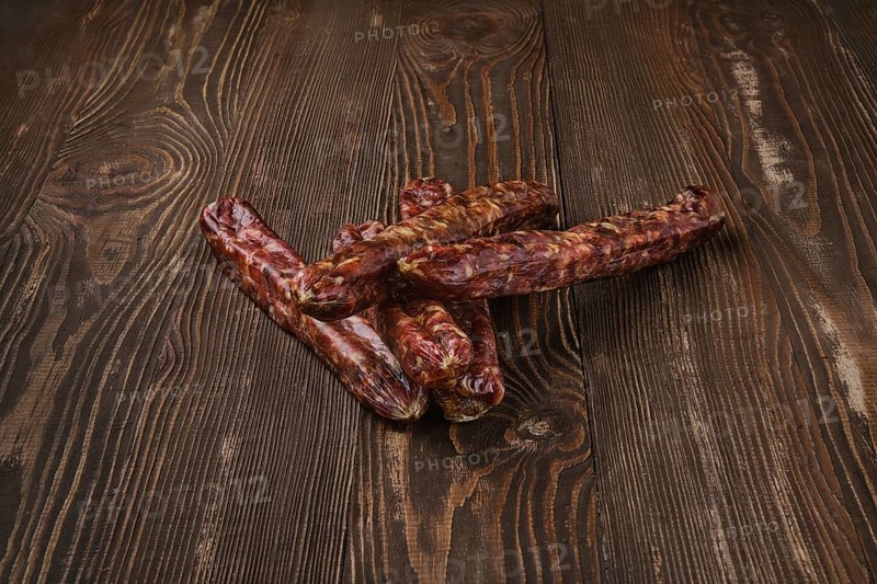 Dried jerked deer and pork sausage on wooden background