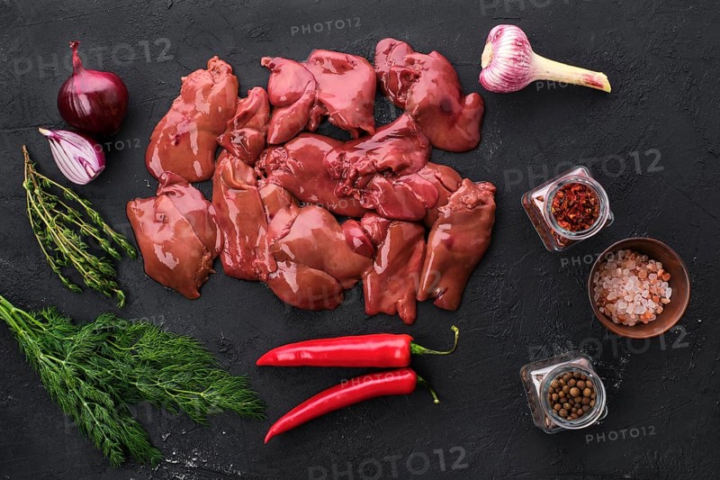 Top view of raw duck liver with spice on black concrete background