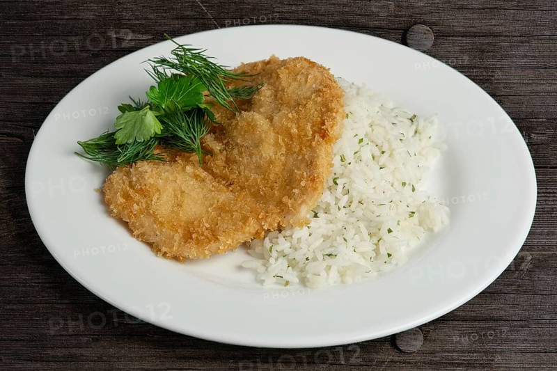 Chicken fillet in breading with rice on wooden table