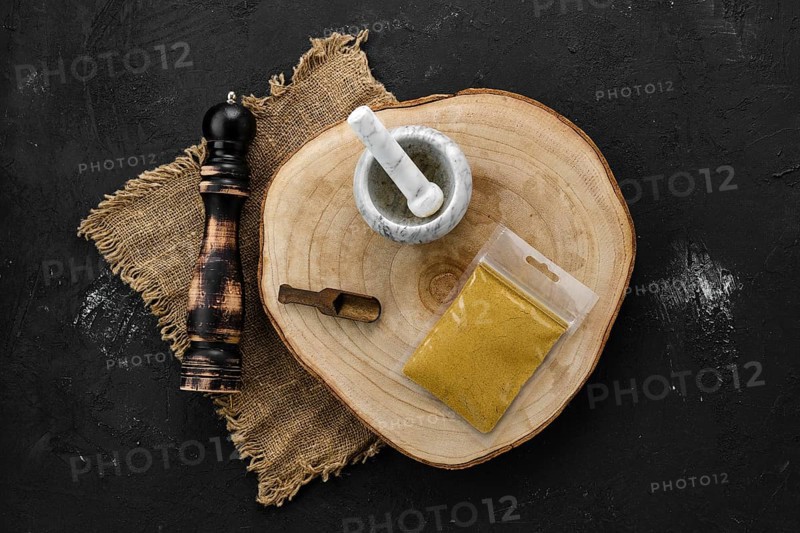 Wooden cross section with curry in plastic package and stone mortar and mill