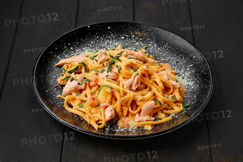 Pasta with salmon and zuccini with grated parmesan on a plate