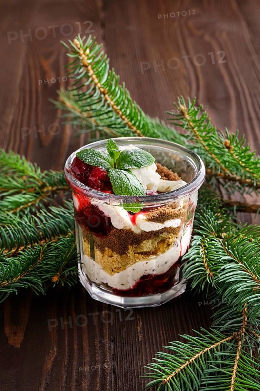 Delicious tiramisu dessert with cherry in rustic pot on dark wooden background