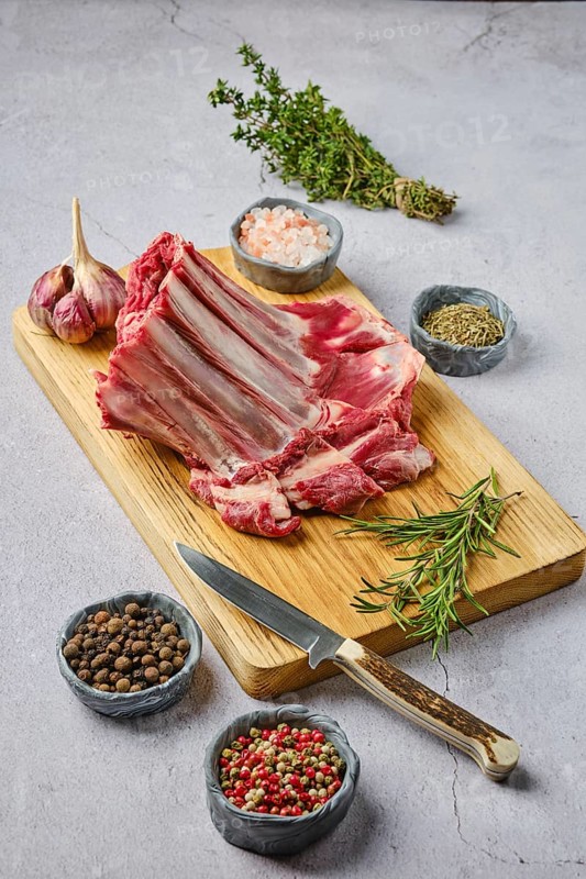 Raw fresh deer ribs with spice and herb over concrete background