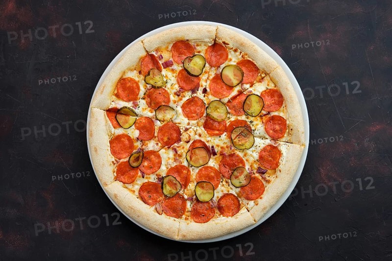 Top view of pizza with pickled cucumber and pepperoni sausage