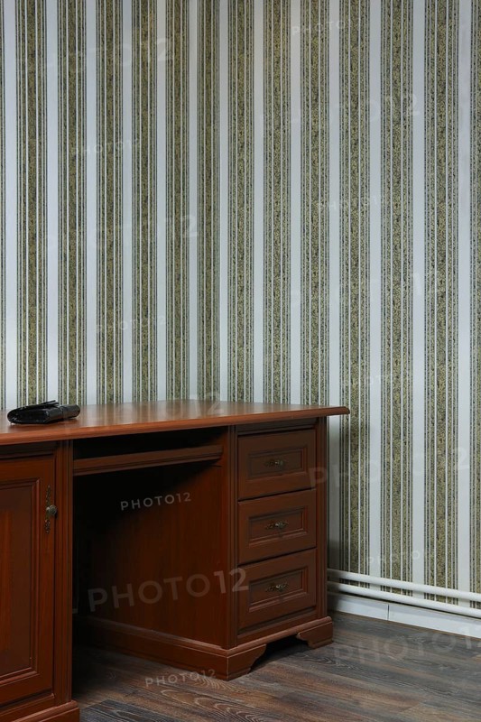 Old wooden table in the corner of the room with striped wallpaper