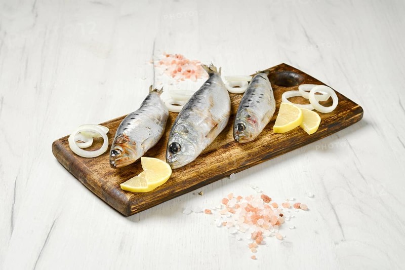 Salted iwashi herring fish marinated in spice on wooden cutting board