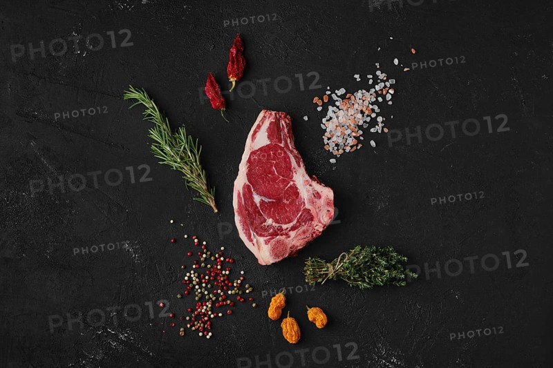 Top view of raw strip steak bone in on dark background