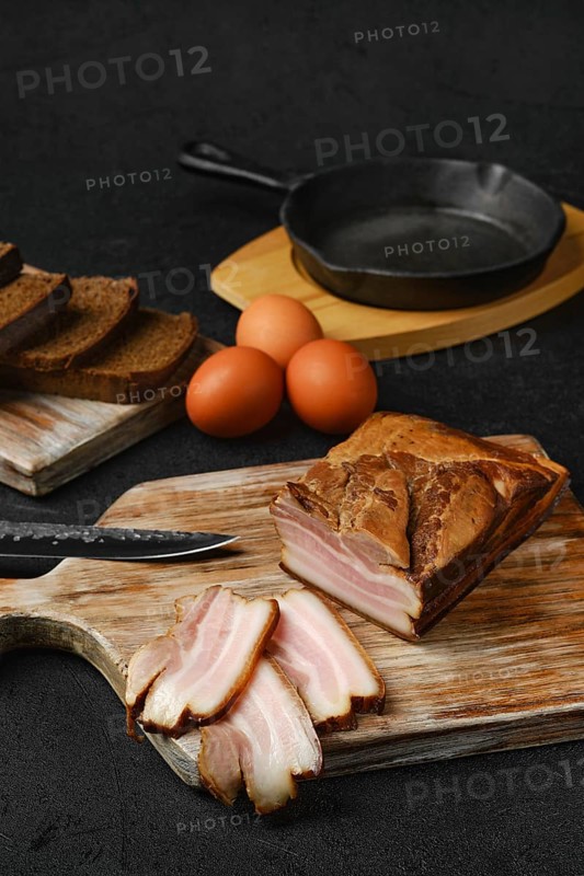 Smoked pork bacon with brown bread and eggs on wooden cutting board