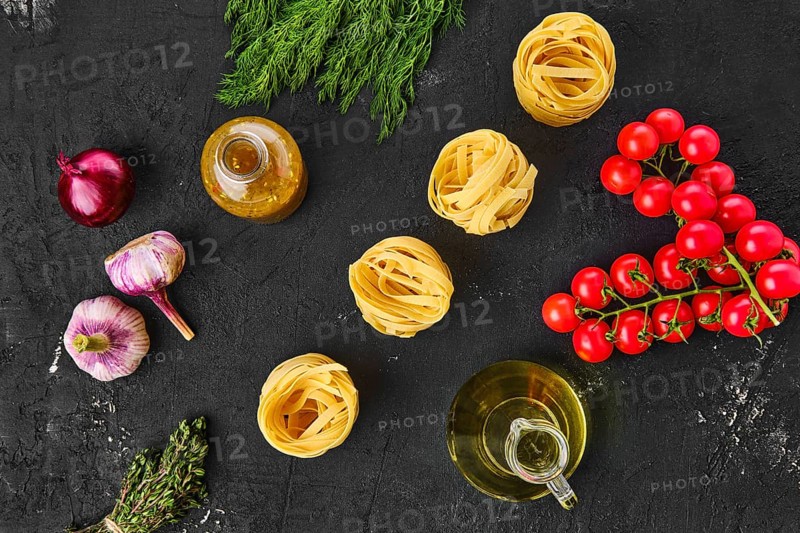 Overhead view of raw tagliatelle with spice and herbs on black background