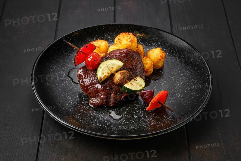 Grilled beef with vegetables and potato balls on a plate