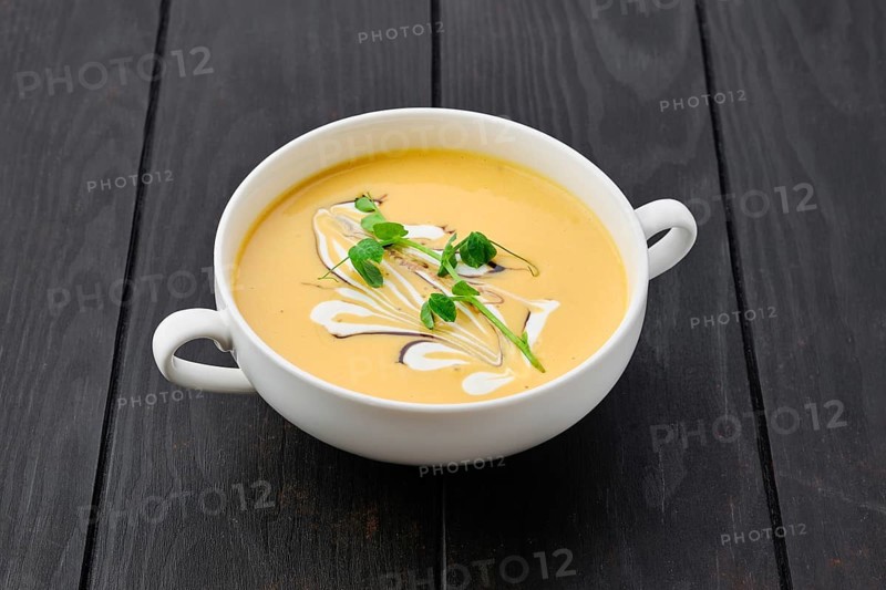 Portion of pumpkin puree soup with barbecue sauce and sour cream