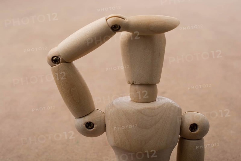 Anatomy doll making a hand gesture on a wooden background