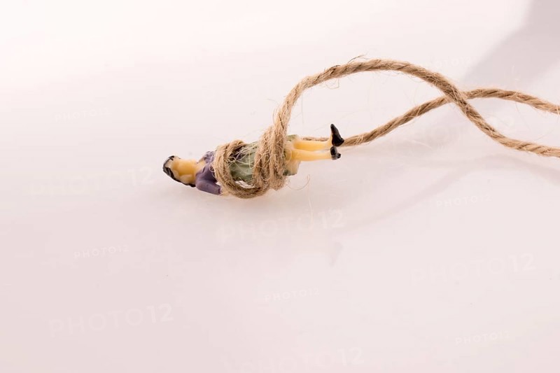 Woman figure lying down tied with a linen thread on a white background