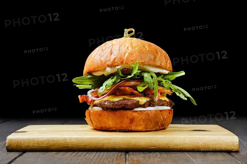 Tasty beef burger with bacon on wooden serving board