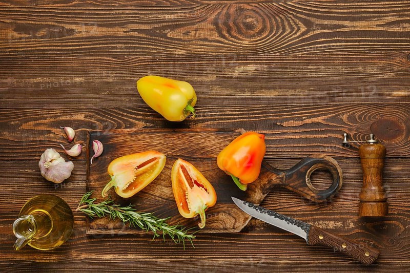 Sweet bell pepper or paprika cut on half and whole on wooden cutting board