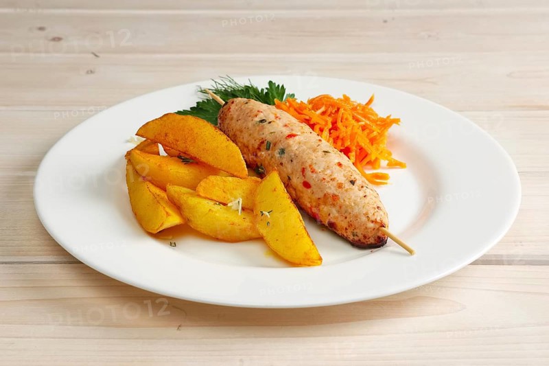 Kebab on skewer with fried potato and spicy carrot