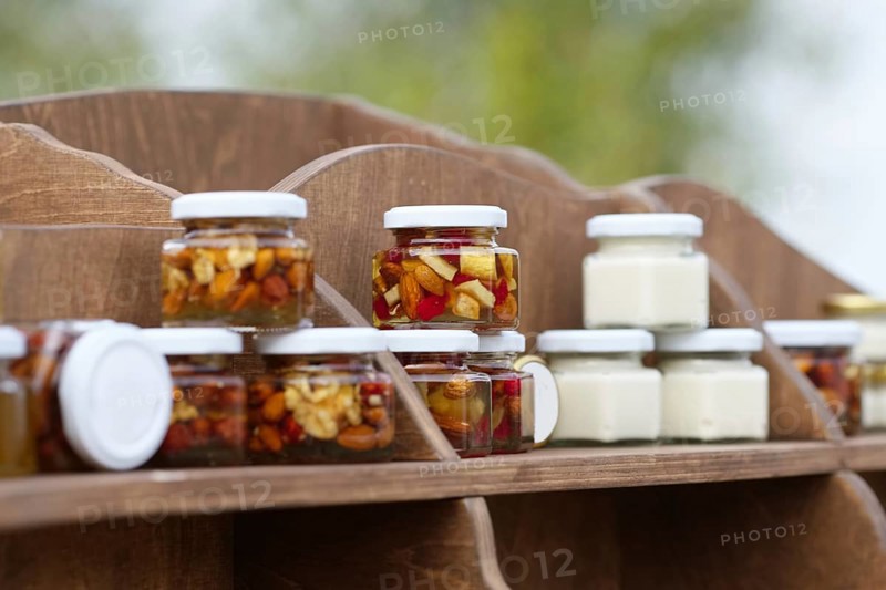 Nuts and honey in small jars on shelf