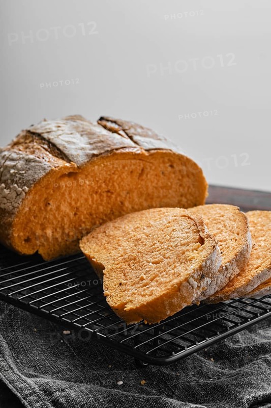 Closeup view of artisan whole grain tomato wheat bread cut on slices on wooden table