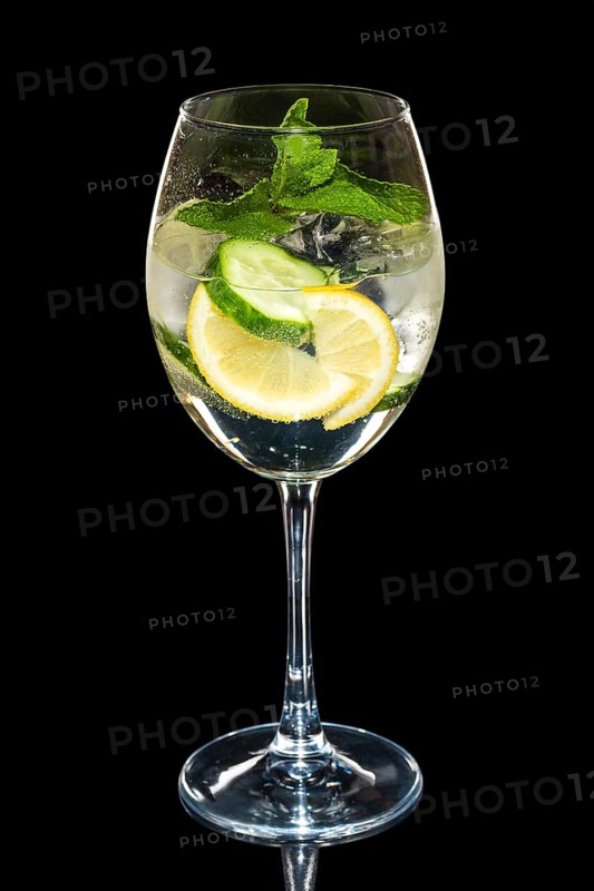 Cold Lemon and cucumber cocktail with a sparkling wine with ice cubes in wine glass isolated on black