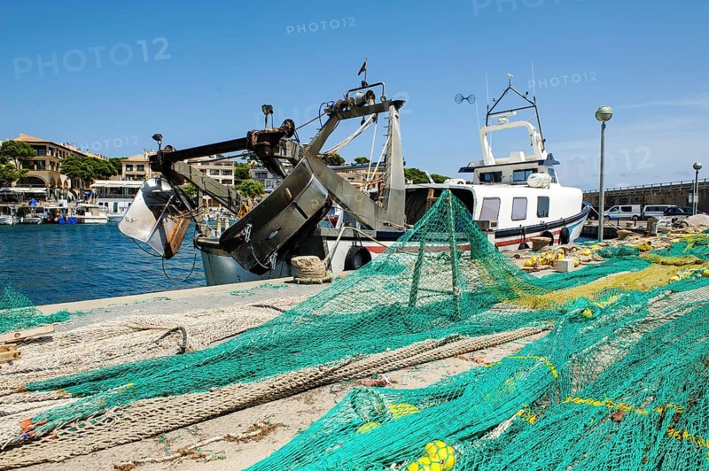 Fishing nets lying stretched out to dry for repair on quay at harbour pier