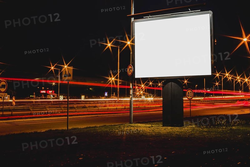 Blank advertisement billboard with blurred traffic lights night