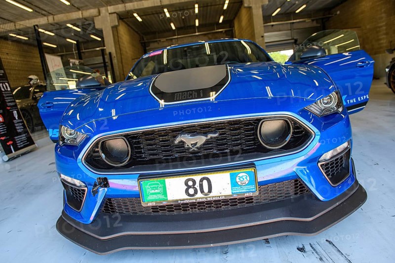 Front view of racing car sports car Ford Mustang Mach 1 standing with open doors in pit of race track