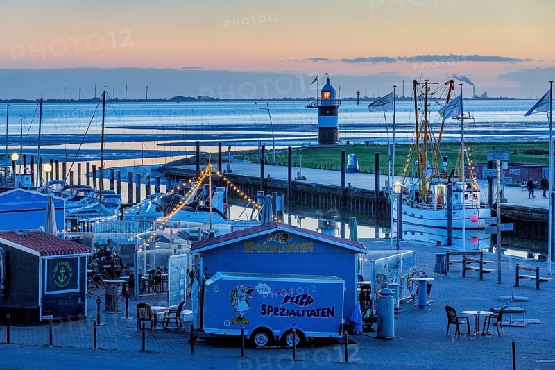 Sielhafen with stalls and lighthouse Kleiner Preusse at the mouth of the Weser at dusk