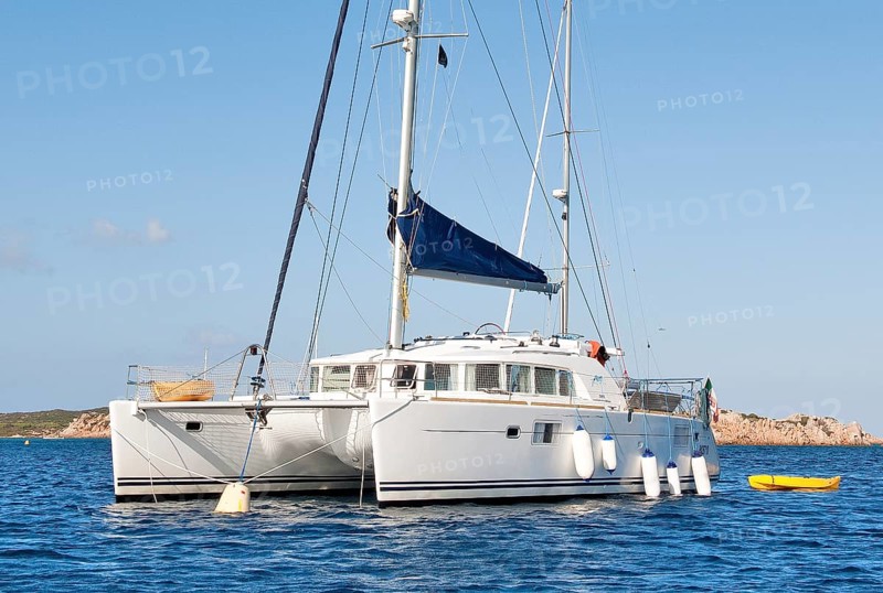 Catamaran with small dinghy moored to mooring buoy