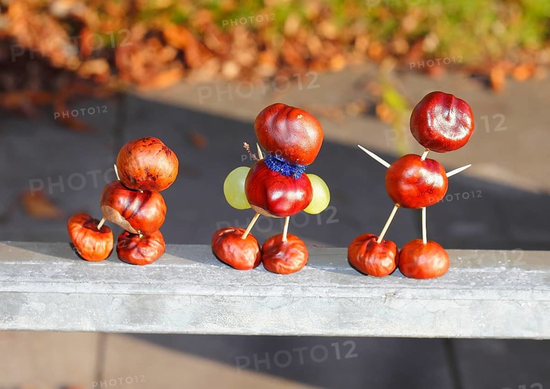 Three chestnut figures with grapes in the evening light