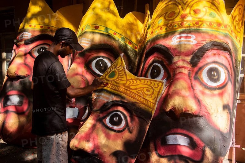 Artisan painting on a face of Ravana idol ahead of Dussehra Festival