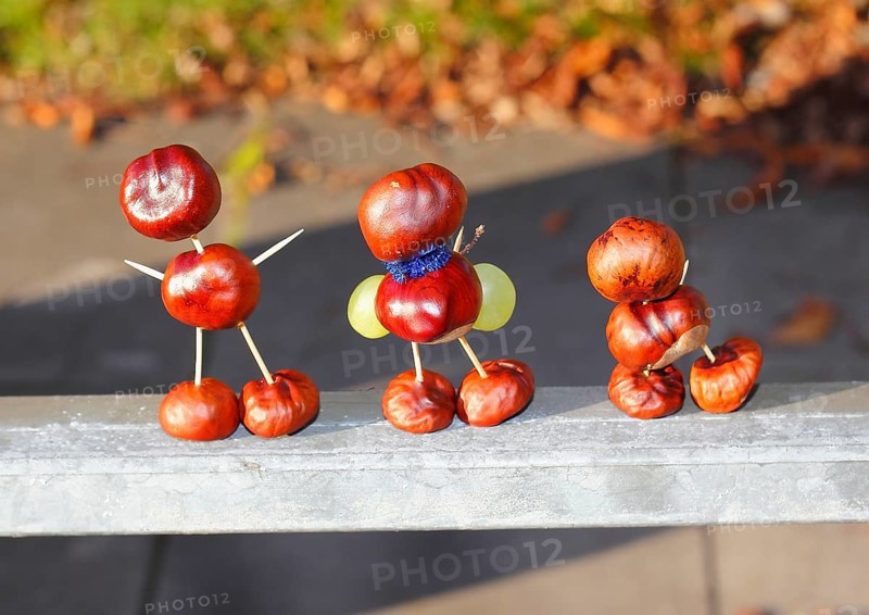 Three chestnut figures with grapes in the evening light