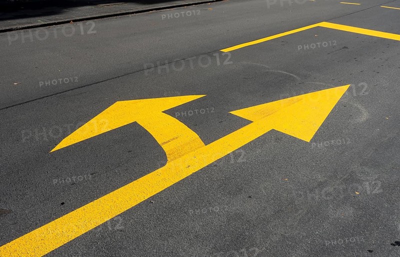 Yellow marking arrow on a road for straight ahead and left turn