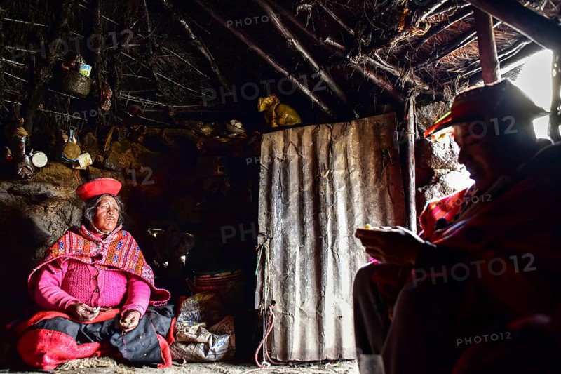 Quechua Indians in traditional dress sitting in their hut