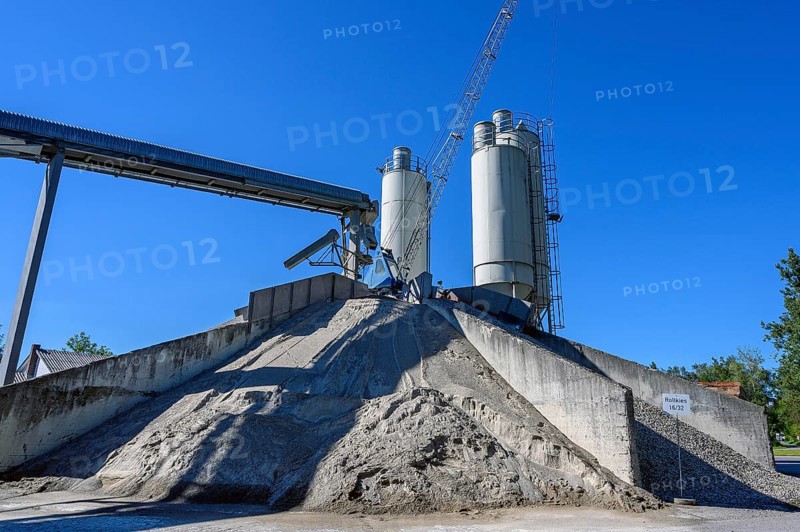 Steel silos and shovel crane with gravel piles and conveyor belt