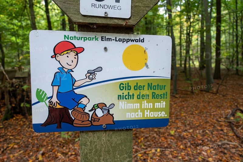 Sign with the inscription Don't give nature the rest! Take it home with you. under hiking signs in the autumnal forest