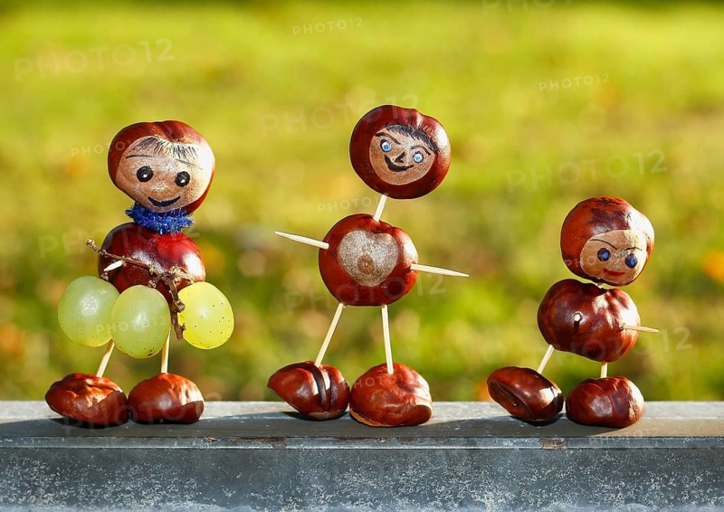 Three chestnut figures with grapes in the evening light