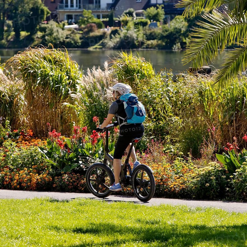 Bicycle rider on the Ruhr valley cycle path with lush vegetation at the reservoir