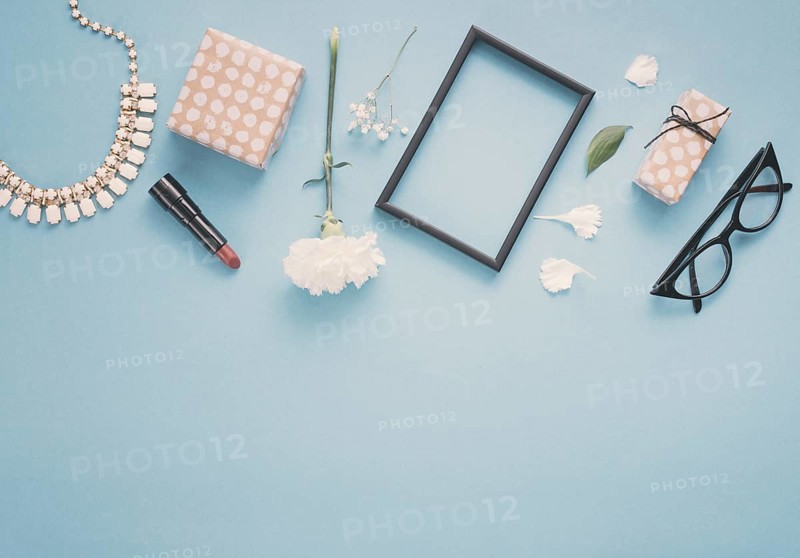Blank frame with flowers gift boxes lipstick table