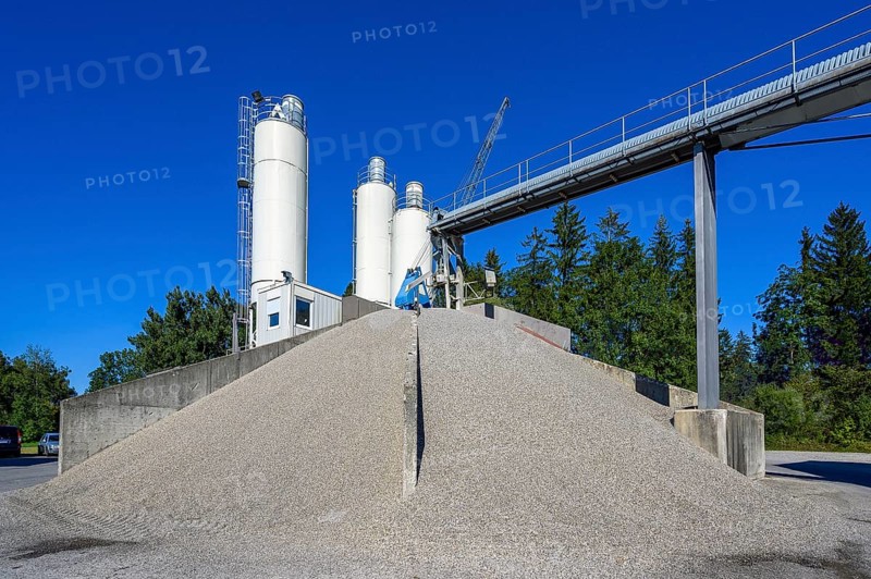 Steel silos and shovel crane with gravel piles and conveyor belt