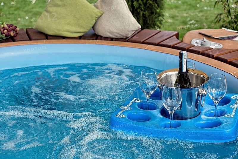 Tray with champagne bucket and three glasses floating in a pool in the garden