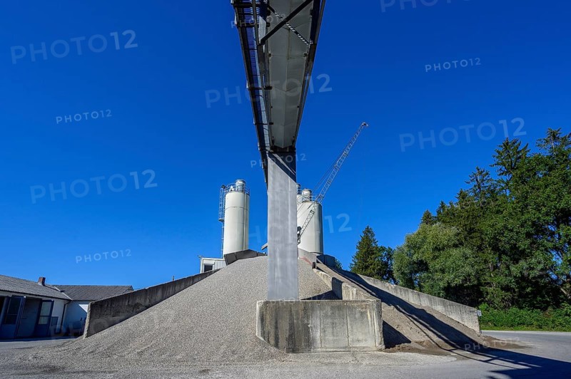 Steel silos and shovel crane with gravel piles and conveyor belt